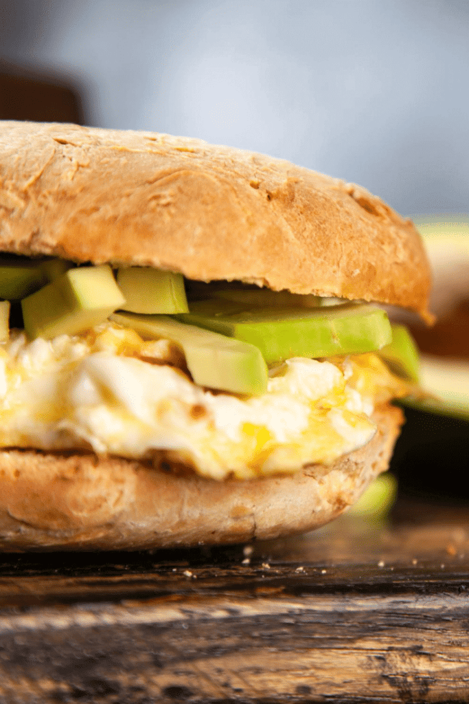 a fluffy egg sandwich on a golden bun with greens and avocado 