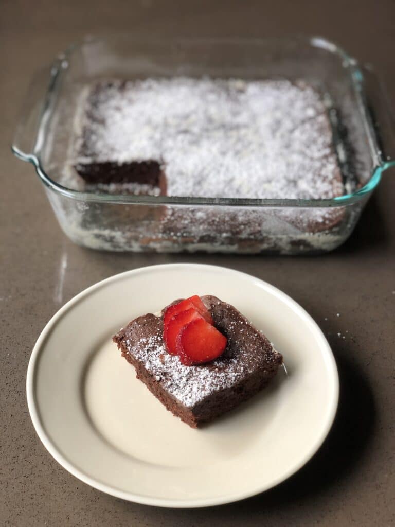 perfectly baked brownies with a strawberry and powdered sugar on top
