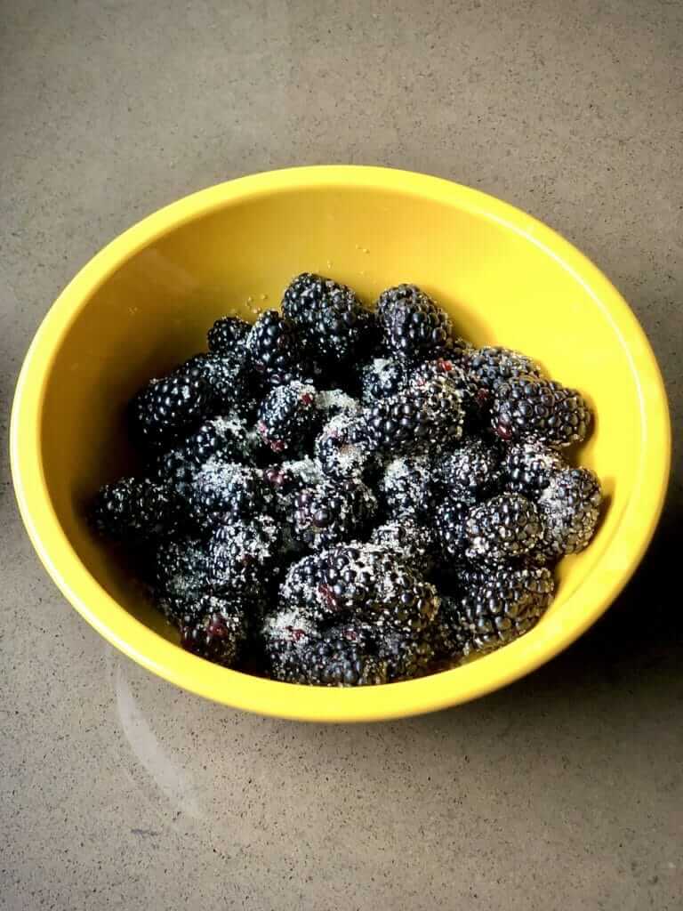 dark blackberries and a golden oat topping in a yellow bowl