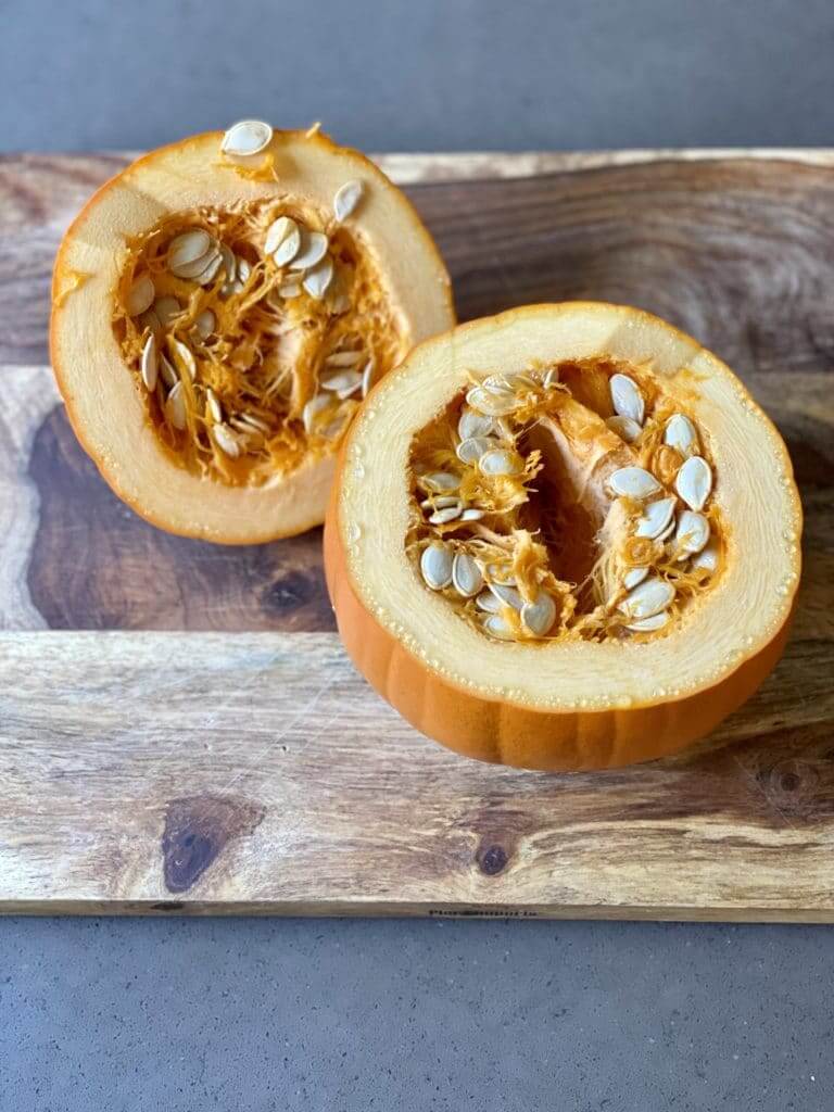 a beautiful sugar pumpkin cut in half with seeds exposed 