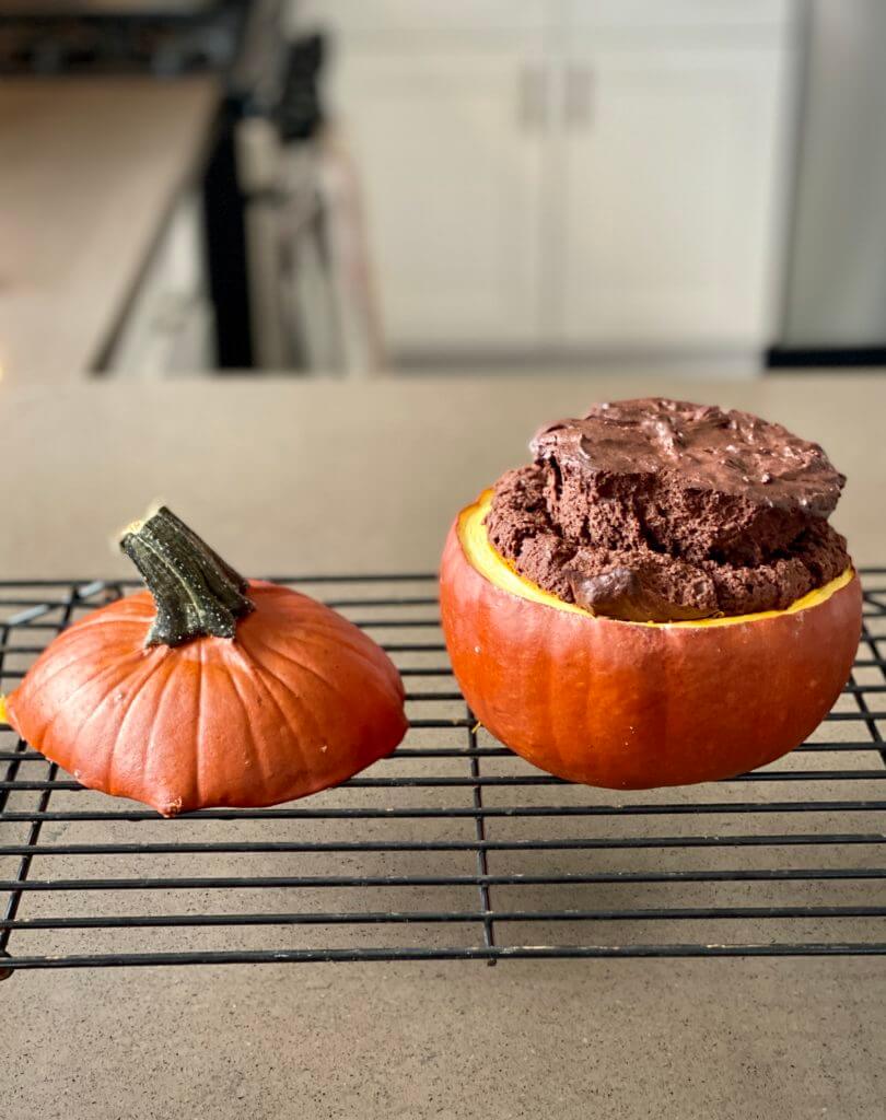 cooked chocolate cake in a pumpkin cooling on a rack