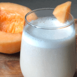 a subtle orange, creamy smoothie with vibrant melon in the background