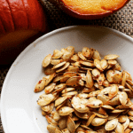 pumpkin in the background with roasted seeds in the forefront