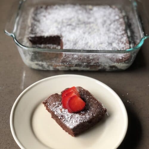 perfectly baked brownies with a strawberry and powdered sugar on top