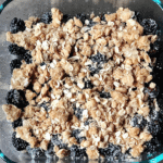 dark blackberries and a golden oat topping in a glass dish
