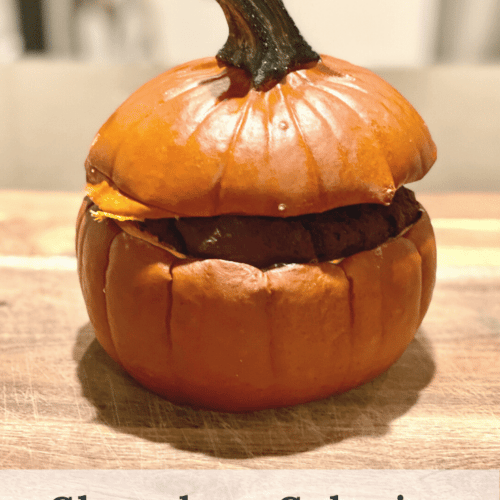 A sugar pumpkin cut in half, both sides covering a chocolate cake inside