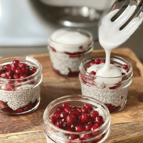 vibrant, crimson pomegranate arils on top of creamy chia seed pudding in mini mason jars